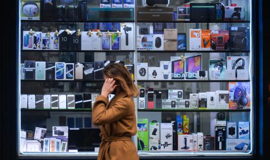 A woman walks by an open shop with mobile phones