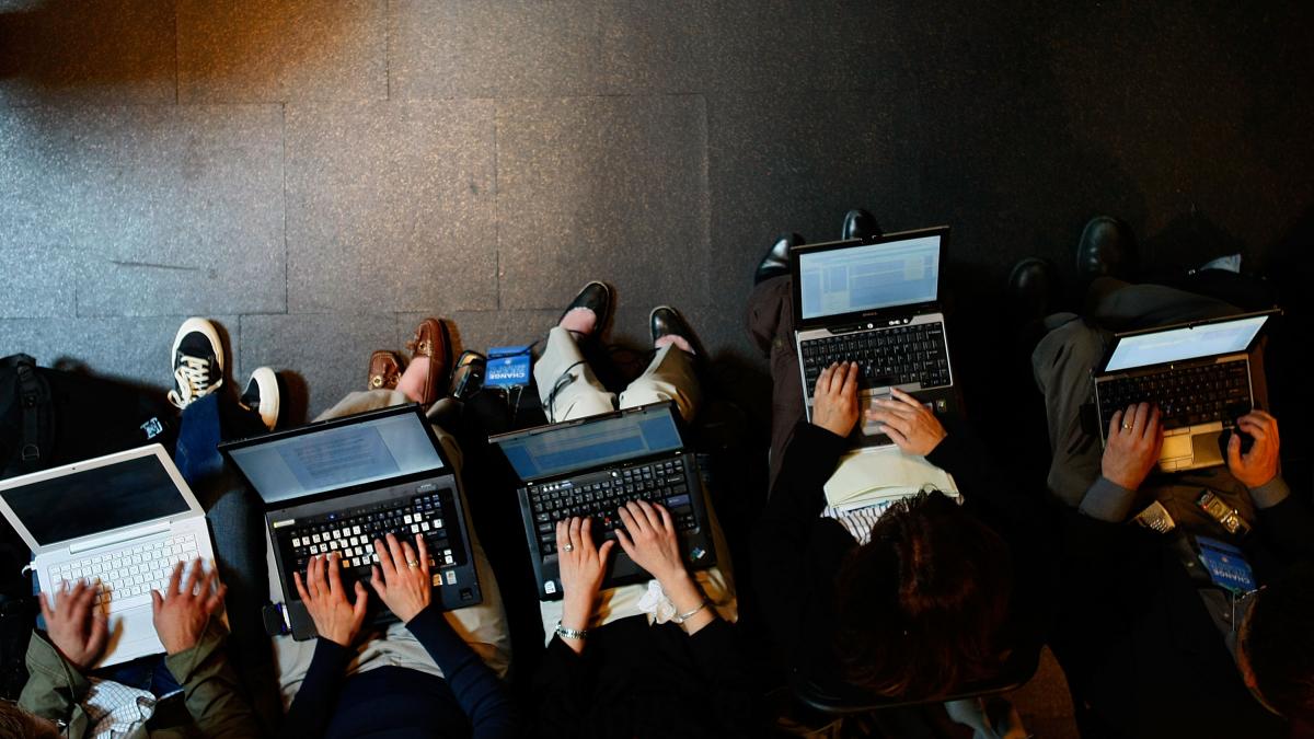 Remote workers sitting in a line on their laptops