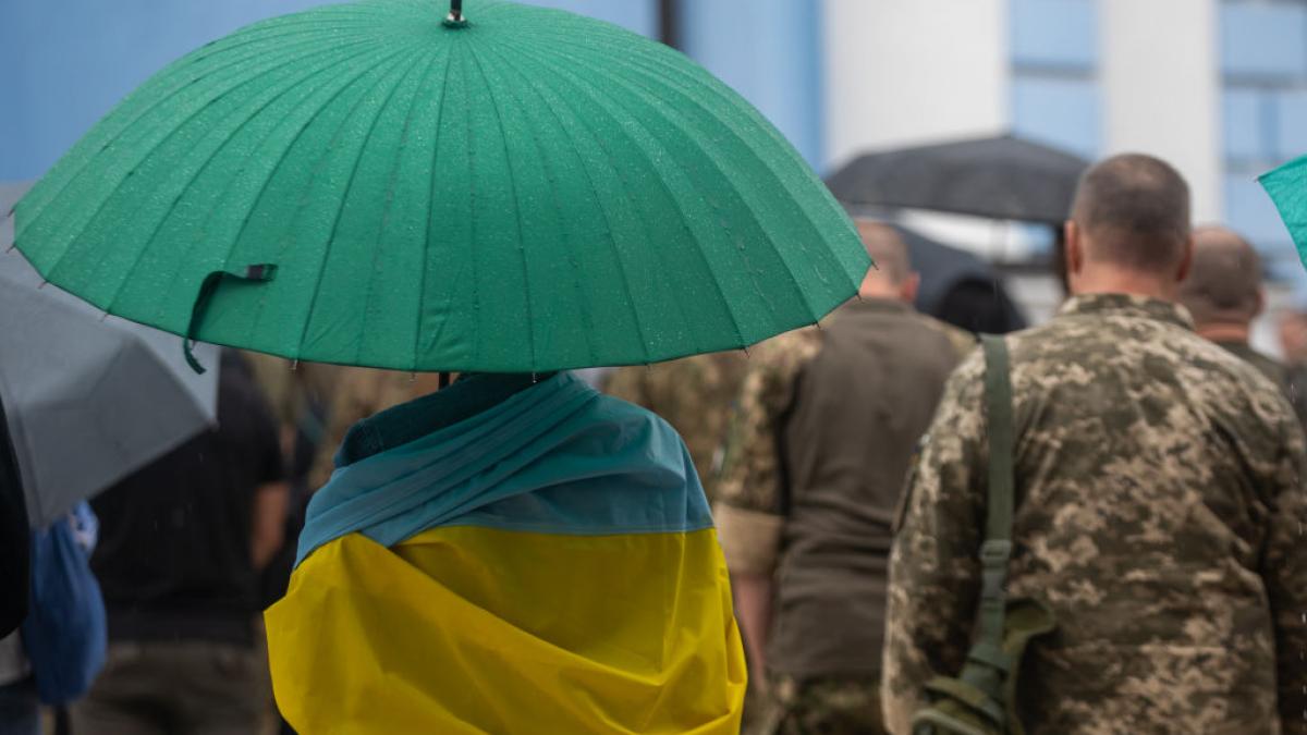 Event visual of man holding Ukrainian flag and a green umbrella