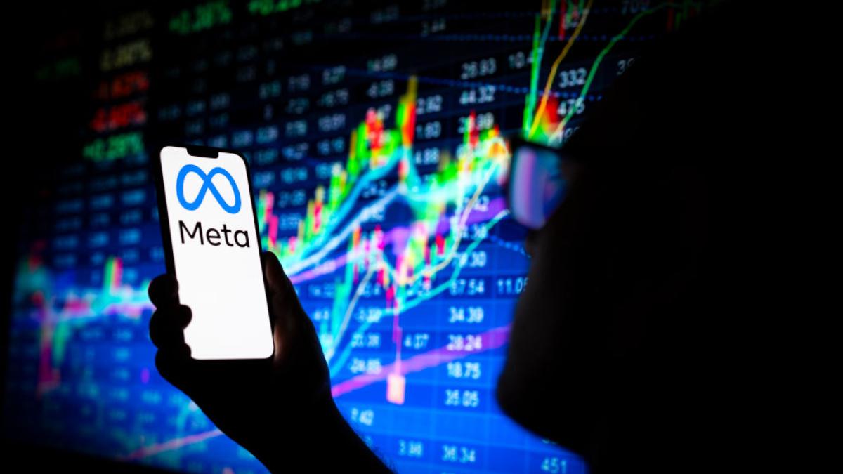 he Meta logo is seen on a phone screen with a stock market prices graph in the background in this illustration