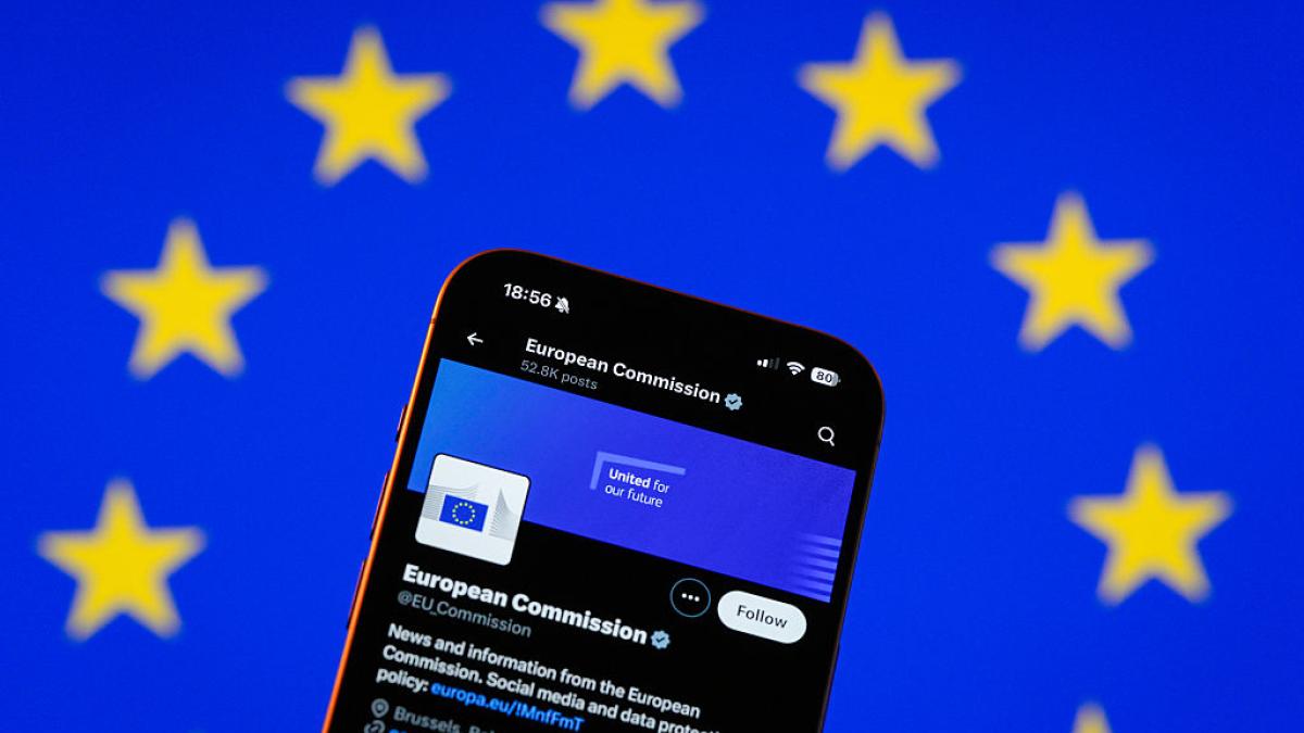 A phone showing the European Commission social media account, over an EU flag.