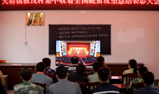 Members of the Communist Party of China (CPC) watch a television screen broadcasting a grand gathering held at the Great Hall of the People to mark the country's accomplishments in poverty alleviation and honour its model poverty fighters, at Banmao village on February 25, 2021 in Liuzhou, Guangxi Zhuang Autonomous Region of China.