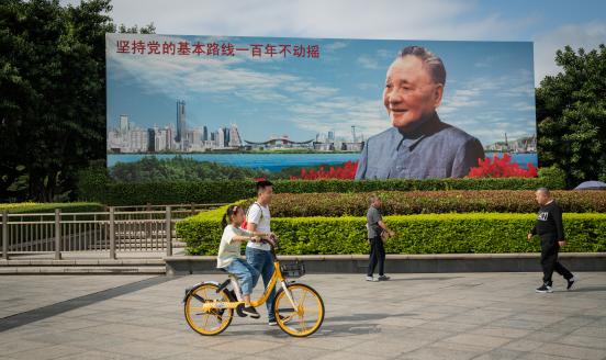 People cycle and walk through Deng Xiaoping Portrait Square in Shenzhen, China, on Saturday, Nov. 21, 2020. 