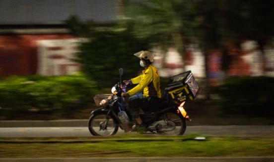 A Meituan food deliveryman rides a motorcycle on the road amid the coronavirus pandemic on April 18, 2021 in Ruili, Yunnan Province of China. 