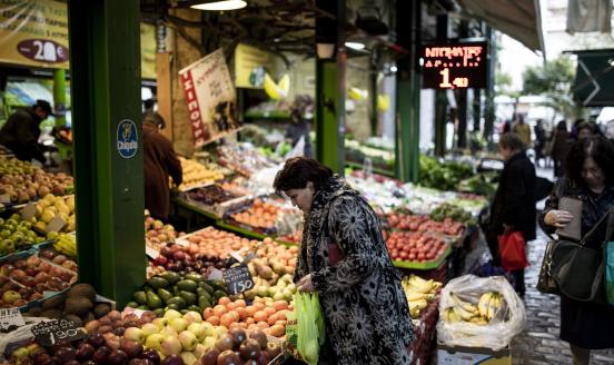 A customer selects fresh fruit from a grocery stall in a covered market in the Athonos district of Thessaloniki, Greece, on Monday, April 6, 2015. Prime Minister Alexis Tsipras's government, elected on promises to end austerity, said it will meet an obligation to pay the IMF 450 million euros ($494 million) this week. 