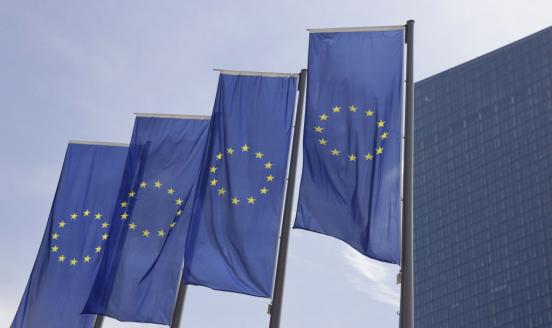 An image of four European Union flags flying high on poles