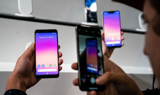 Picture of hands holding mobile phones with a pink and blue gradient on the screens.