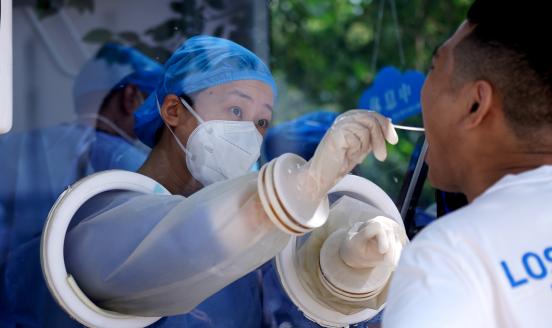 A medical worker in a COVID-19 nucleic acid testing cabin takes swab sample from a resident for COVID-19 nucleic acid test on August 22, 2022 in Zhengzhou, Henan Province of China.