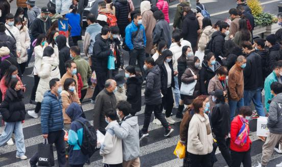 People with protective masks walk across zebra crossing on December 11, 2022 in Shanghai, China