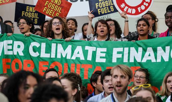 picture of protestors at COP28, with a sign stating 'climate finance for equity'