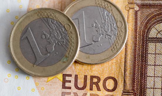 a picture of 2 one euro coins sitting on a 50 euro bank note