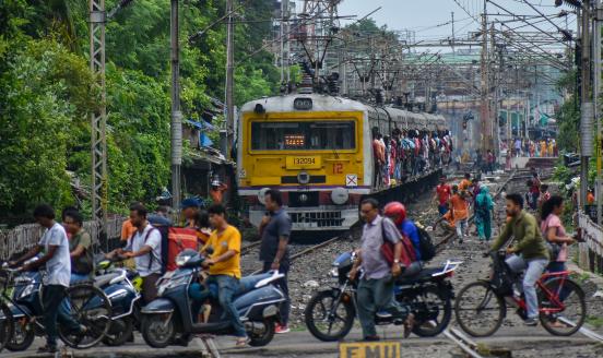 People are crossing a railway track as a train is leaving the station in Kolkata, India, on July 22, 2024. It is expected that the railway is being allocated a substantial part of the budget to increase efficiency in railway travel. More sleeper coaches and Vande Bharat trains are being announced, allegedly according to reports. (Photo by Debarchan Chatterjee/NurPhoto via Getty Images)