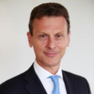 Headshot of smiling man in suit with a light blue tie