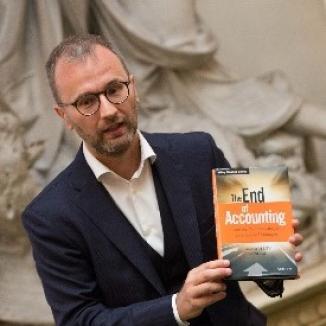 Man in a suit holding a book titled 'The end of Acounting'