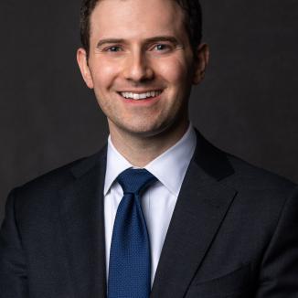 A middle-aged man in a suit smiling at the camera