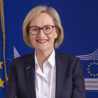 A woman with blonde hair, in white shirt and black blazer smiling at the camera