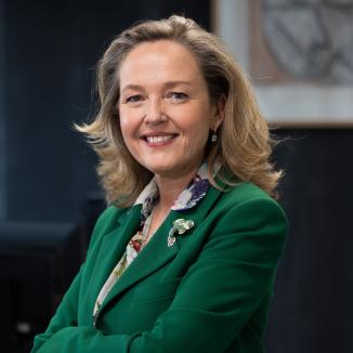 a woman with sholderlength blonde hair, in a green blazer, smiling at the camera